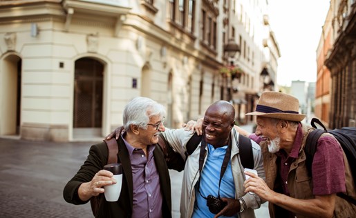 Three older gentleman laughing walking through an old town.